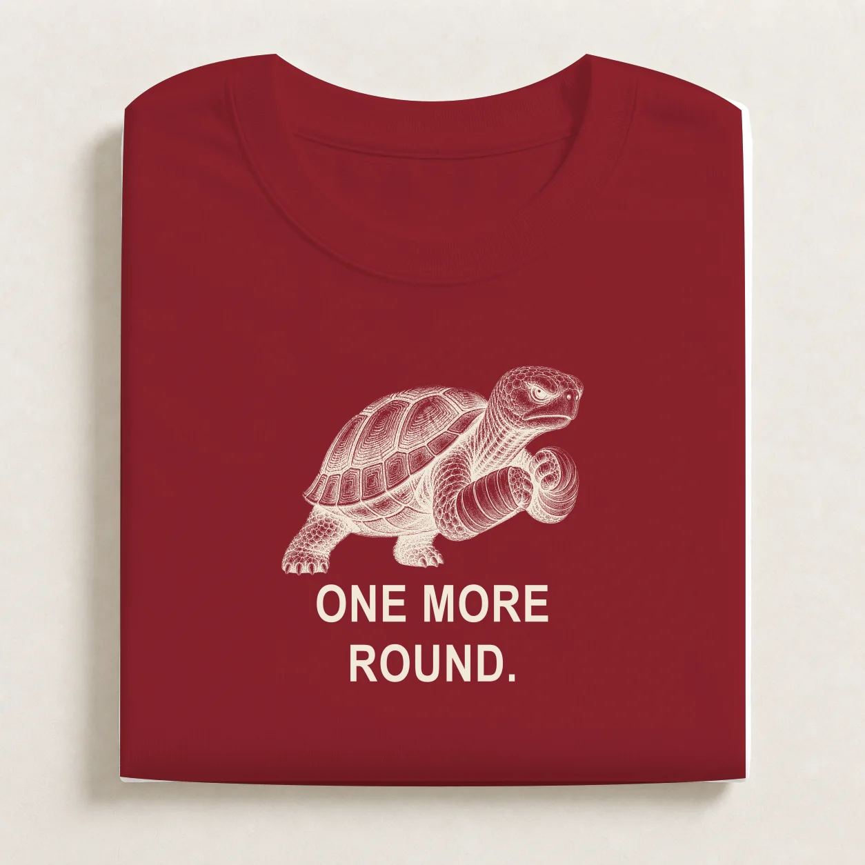 One More Round printed on a folded Brick Red T-shirt.