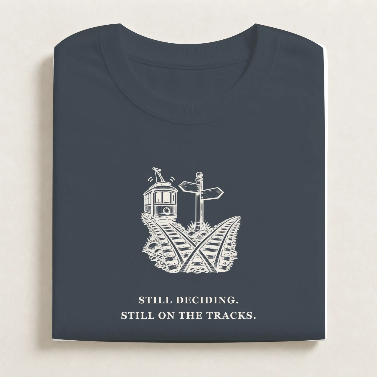The Trolley Problem printed on a folded Petrol Blue T-shirt.